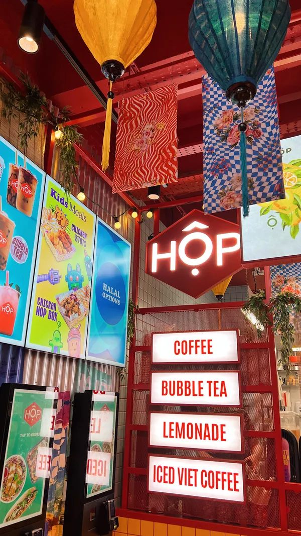 The video showcases Hop Vietnamese, a restaurant in London.  It features various dishes, including the Chicken Coconut Curry HOP Box, Chargrilled Pork HOP Box, dumplings, Viet Fried Chicken Dippers, and Raspberry Lemonade. The food is presented in aesthetically pleasing takeout containers.  The main focus is on showcasing the food and drink options available at the restaurant, highlighting the ease of ordering via touchscreen kiosks.