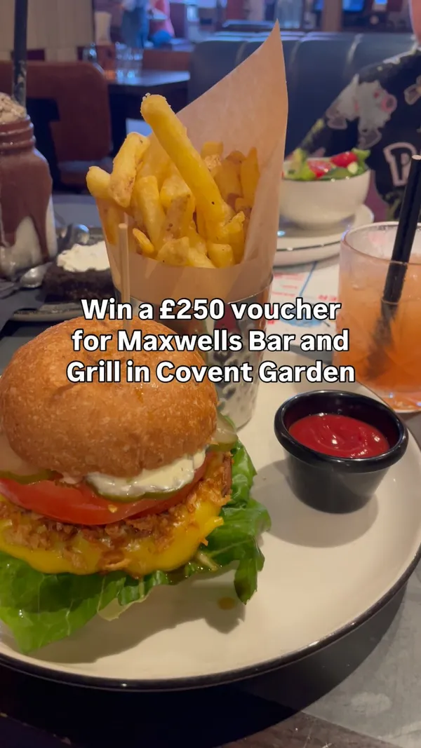 The video promotes a "design your own burger" competition for children at Maxwell's Bar and Grill in Covent Garden. It opens with a shot of a burger and fries, then shows children participating in the activity by drawing their burger ideas on a promotional sheet. Text overlays are used throughout to explain the competition details, including the prize of a £250 voucher and the winning design being featured on the menu. The setting is inside the casual, family-friendly restaurant.
