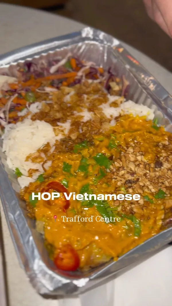 This video showcases a family's experience at HOP Vietnamese Street Eats in The Trafford Centre. The video begins with a view of the restaurant's exterior, then transitions to the ordering process via touchscreen kiosks, showing a detailed look at the menu and ordering options for various dishes and drinks. The family then collects their food, which is presented in aesthetically pleasing packaging. The video ends with them enjoying their meal, which includes prawn dumplings, ribs, chicken and other items from the restaurant. Dietary information is shown on the touch screen menu and includes vegetarian options. The video primarily focuses on the ordering, collection, and enjoyment of the meal.
