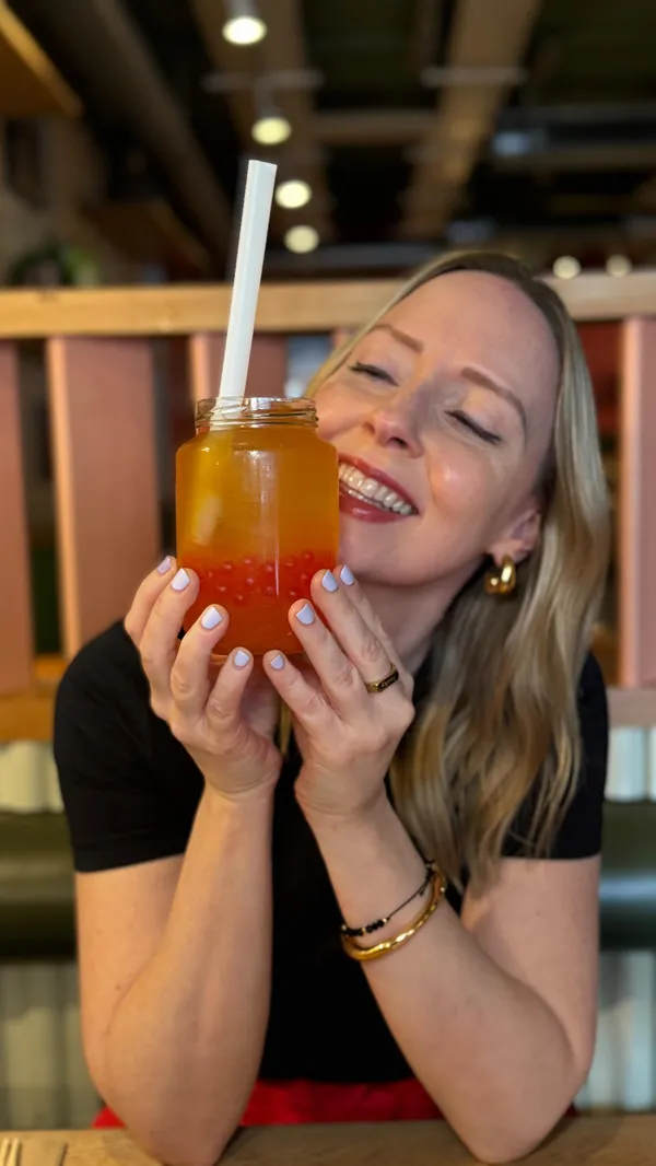 The video shows a woman walking towards Rosa's Thai restaurant. Inside, she is shown drinking a bubble tea, eating crispy squid, a prawn curry dish with rice, and a chocolate brownie dessert with ice cream and caramel sauce. The food items are presented clearly. The main focus is showcasing the food and the dining experience.