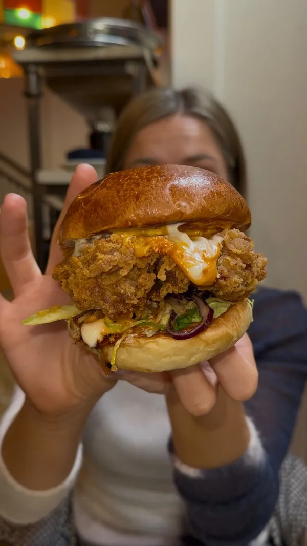 The video presents a top 5 list of chicken burgers in London. It features the influencer trying burgers from five different establishments: The Cadogan Arms, Fowl, Fat Phil's, Butchies, and 20ft Fried Chicken. The video includes close-ups of the burgers, shots of the influencer eating and reacting, and brief glimpses of the restaurant interiors. Each burger is numbered according to its ranking in the list.