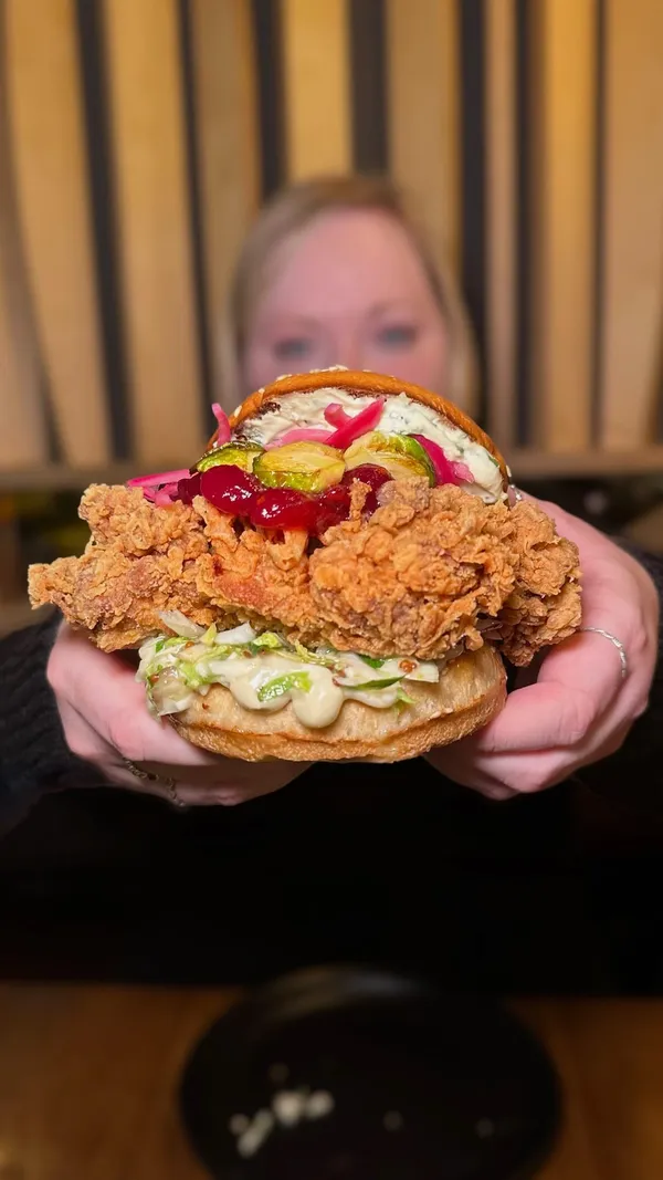 This video showcases Christmas specials at Wingmans Chicken in Soho and Kilburn.  The video highlights several dishes: Gingerbread Berry BBQ Wings with cranberry and gingerbread BBQ sauce; Sleigh My Name Chicken Burger with crispy chicken thigh, garlic and herb cheese mousse, sprout and celeriac slaw; Loaded Tinsel Tots with crispy potato tots, roasted garlic mayo, blue cheese crumb, and bacon; Cauli Cheese Croquettes (Soho only), and Winter Spiced Appletini. The food is presented attractively, with close-up shots emphasizing textures and details. No specific dietary information is provided.