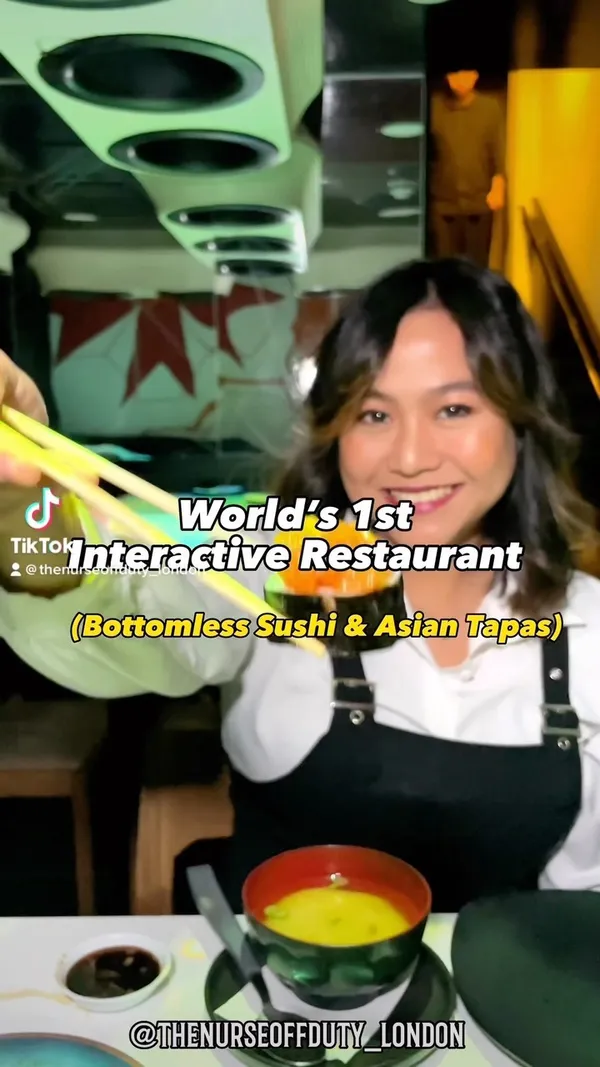 The video showcases Inamo Restaurant, highlighting its interactive dining experience.  The influencer orders food via a touch-sensitive table, showing a variety of sushi and Asian tapas dishes, including salmon tataki, various sushi rolls, and other appetizers. The food is presented attractively on plates, with close-up shots emphasizing textures and colors.  The video emphasizes the fun, interactive aspect of the restaurant with shots of games available on the table and friends enjoying their meal. No specific dietary information is explicitly mentioned.