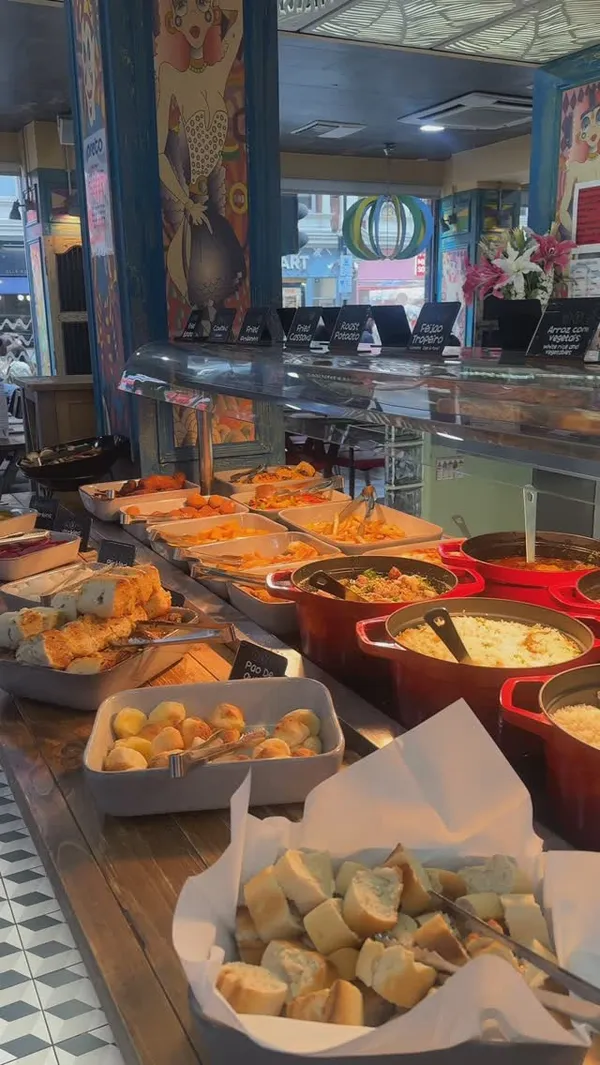 This video showcases the Preto restaurant, a rodizio grill in London's West End. It features a buffet-style setup with various food options, including fried banana, coxinha, fried cassava, roast potatoes, and more. The video also shows a salad bar with sweet corn, cucumber, and other vegetables. A cocktail is presented, followed by a server carving grilled sausage and beef at the table. The video concludes with shots of desserts like flan and cake with dulce de leche. The main focus is on the variety of food and the dining experience.