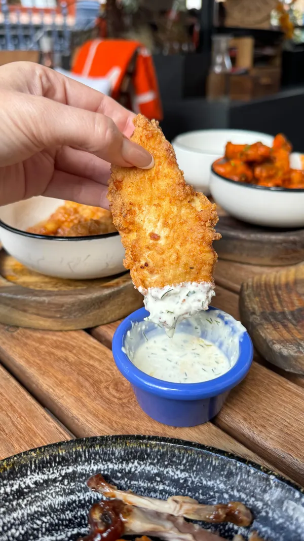 The video showcases Maxwell's Bar and Grill in Covent Garden, London. It highlights their 90-minute bottomless wings deal for £20, including a beer or wine.  Five wing flavors and tenders are shown. The video also features their happy hour cocktail deals with a roulette wheel for discounts. The setting is primarily the bar's outdoor terrace, with some interior shots of the bar itself.  The food presentation is in small bowls on wooden platters. The drinks are shown in stylish glasses. No specific dietary information is provided.