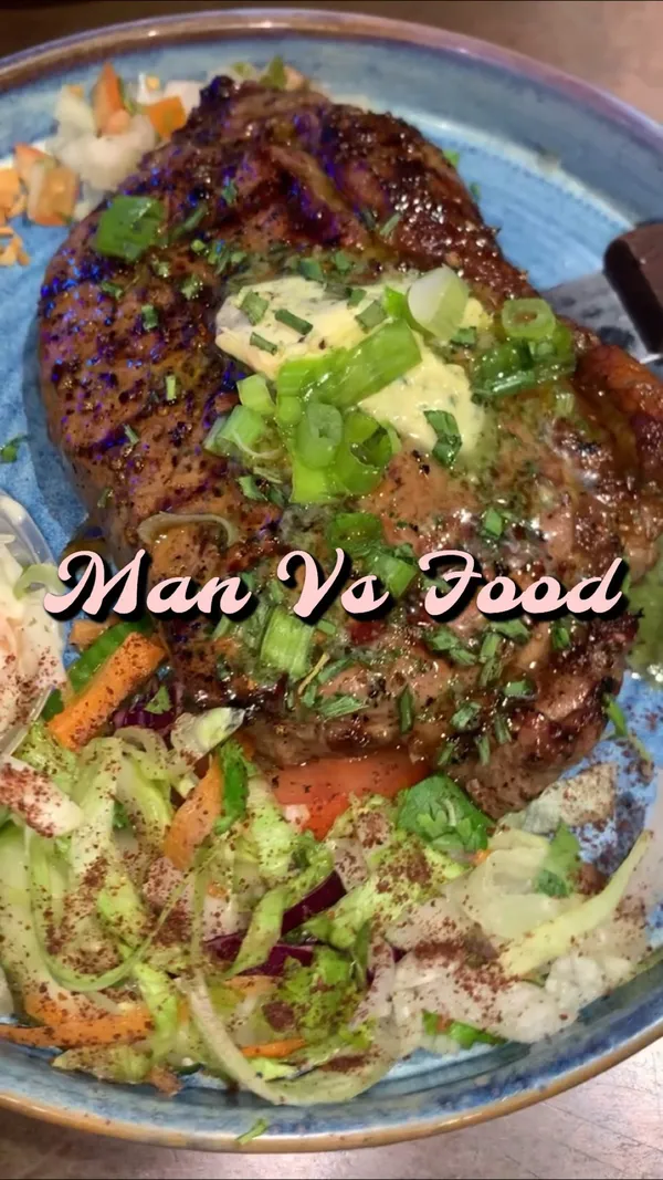 The video showcases Man vs Food London, a restaurant in Isleworth.  It highlights various menu items including a Krispy Kreme burger with two glazed doughnuts and a fried egg, cornflake-coated chicken tenders with cheese, buffalo chicken wings, a large steak with cheesy Mac and cheese, and chicken and waffles.  The presentation focuses on close-up shots emphasizing textures and portion sizes.  No specific dietary information is provided. The main focus is showcasing the food's visual appeal and variety.