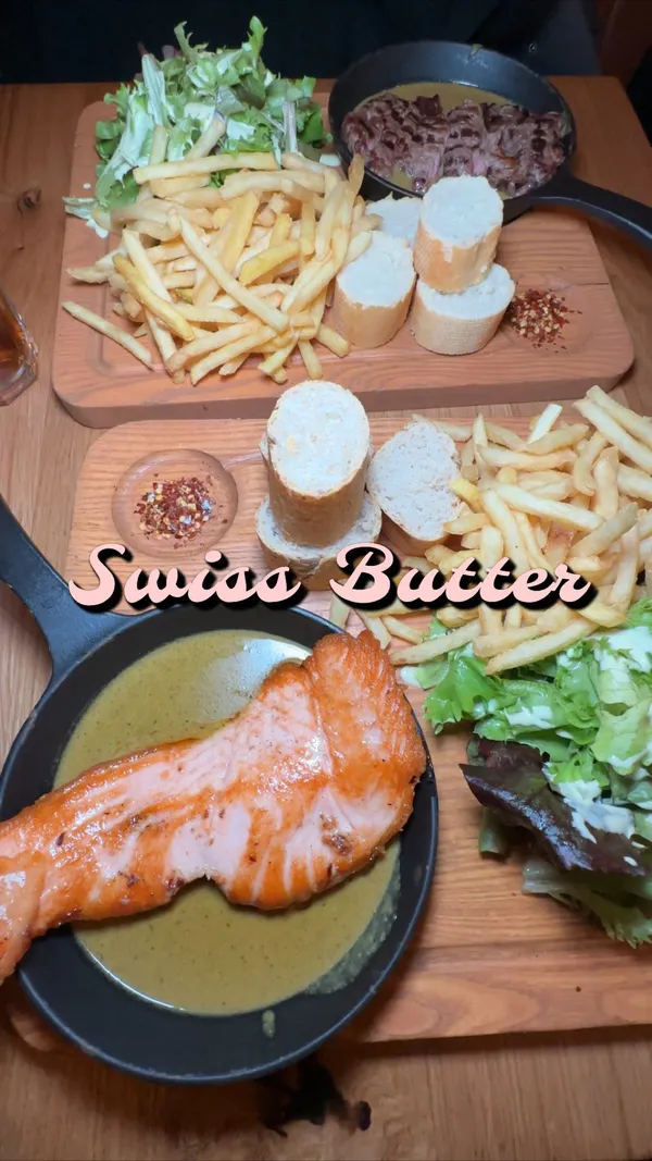 This video showcases a meal at Swiss Butter in Holborn, London.  The food includes a ribeye steak (medium-well), salmon with a tangy, buttery sauce, french fries, bread rolls, and a side salad.  For dessert, they had the 'pan perdu' which includes caramel sauce and ice cream. The presentation is visually appealing, with dishes served in cast iron pans and the food styled nicely.
The video's focus is on the food and the reviewer's experience of the restaurant.