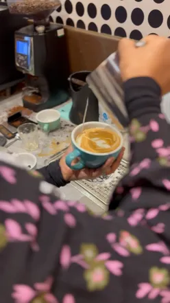 First attempt at latte art with foamy milk in a cafe setting, showcasing barista skills and coffee creativity.