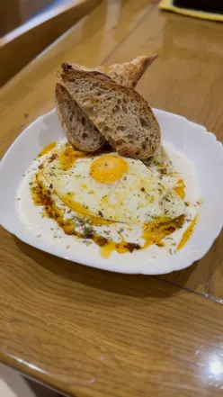 Çılbır with poached eggs, Greek yogurt, garlic, spices, and za’atar, served with sourdough from Companio Bakery.