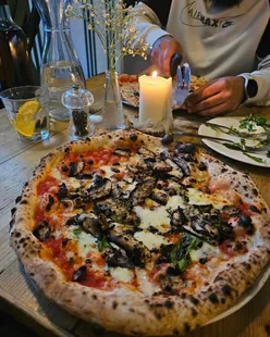Stone baked pizza at Rudy's Ancoats, enjoyed with family in a cozy setting, offering halal and veggie options.