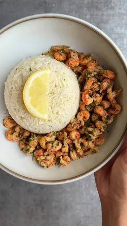 Crayfish in spicy garlic butter with lemon garlic rice, garnished with parsley, embodying a fresh summer seafood vibe.