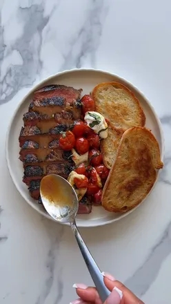 Charred steak Caprese with blistered balsamic tomatoes, gooey mozzarella, fresh basil, and crusty sourdough, perfect summer meal.