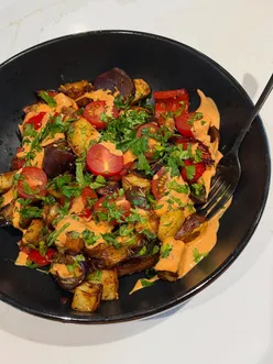 Summer tray bake with lamb merguez sausages, roasted red peppers, potatoes, red onion, tomatoes, parsley, and harissa mayo.