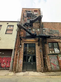 New burger spot under renovation on Faraday Street, Manchester, featuring open kitchen, custom Coca-Cola machine, pastel interior.