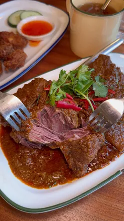 Singaporean beef rendang, Hainanese fried pork chop, and lemongrass wontons at Singapulah Restaurant in London.