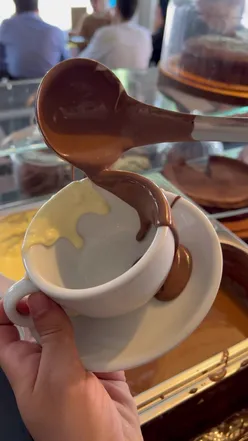 Rich hot chocolate with whipped cream in a cozy London café, perfect for chocolate and coffee lovers.