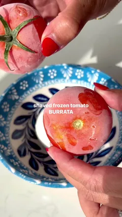 Shaved frozen tomato and burrata dish, viral food trend, fresh and creamy, garnished with herbs, worth the hype.