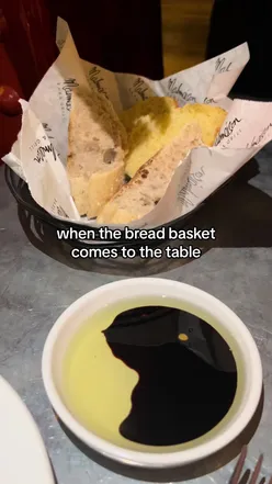 A bread basket filled with fresh bread, served with olive oil and balsamic vinegar for dipping.