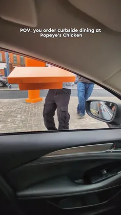 Curbside dining at Popeyes with a wooden tray of fried chicken in a car at the new UK drive-thru on Bury New Road.