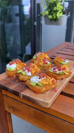 Mini breakfast hashbrowns topped with avocado, scrambled eggs, Greek yogurt, and bacon crumb; a boujie brunch recipe.