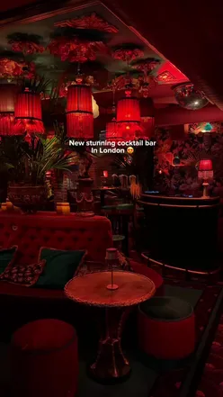 Colorful cocktails on a bar counter in a new Soho London bar, garnished with fresh fruit and herbs.