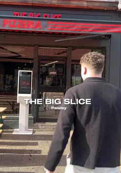 Large pepperoni pizza slice with honey at The Big Slice in Paisley, enjoyed outdoors in sunny weather, Scotland.